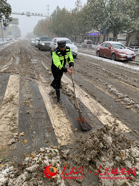 雄縣交警在風(fēng)雪中清理道路積雪。陳達(dá)攝