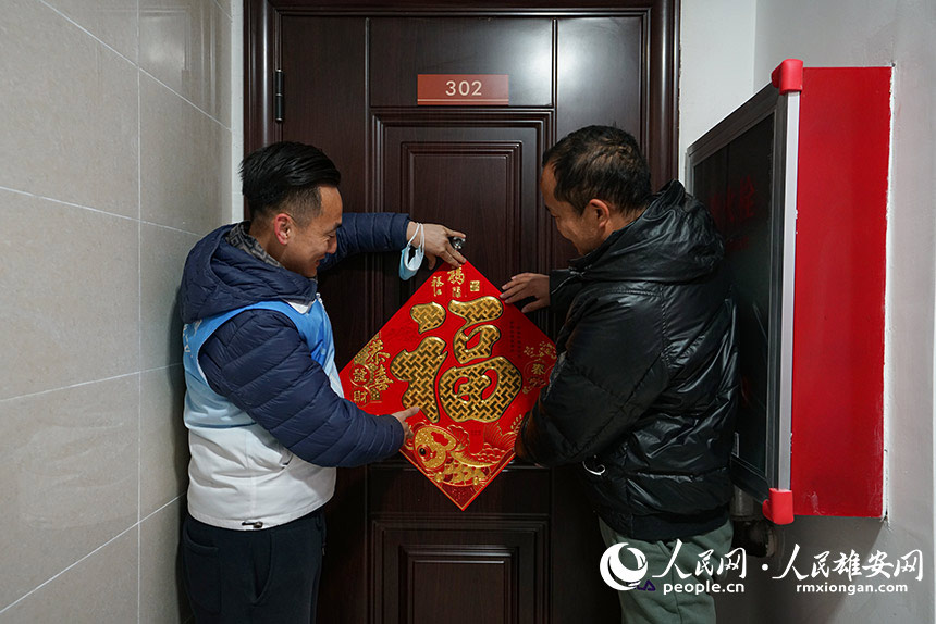 春節(jié)將至,雄安容東片區(qū)社區(qū)工作人員為居民的新房貼上福字。圖為雄安集團(tuán)志愿者正在給新房貼福字。人民網(wǎng) 李兆民攝