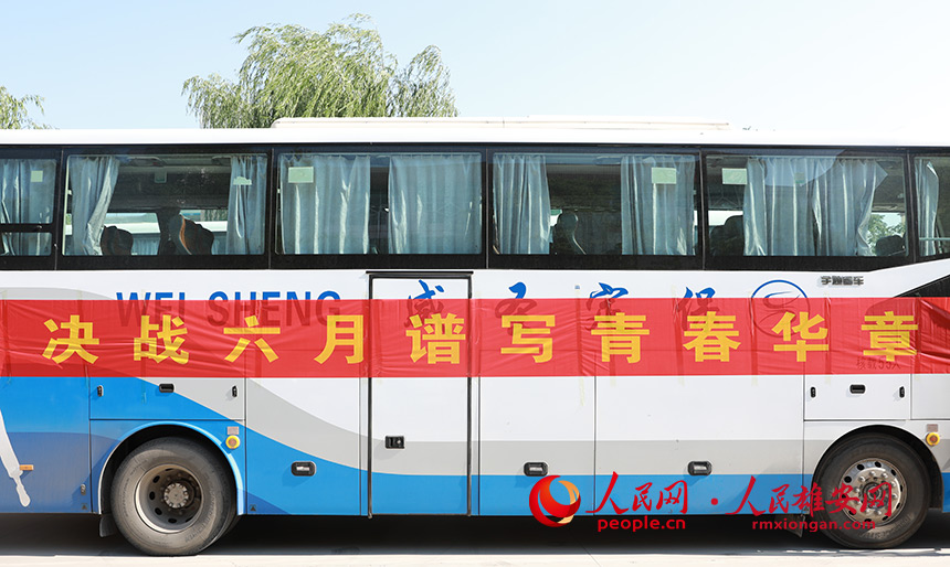 容城中學(xué)考點(diǎn)內(nèi),送考大巴上張貼了加油橫幅。人民網(wǎng) 李兆民攝