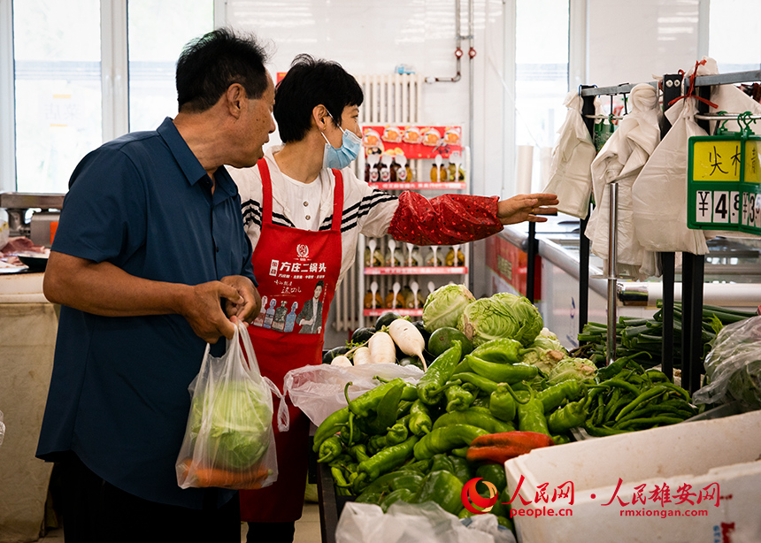 菜店內，工作人員正在為顧客提供幫助。出門就是菜店，吃飯不發愁，成為容東片區居民的日常。人民網?宋燁文攝