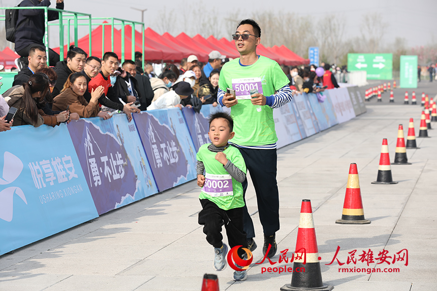 2023雄安半程馬拉松現場，父親帶著兒子參加家庭夢想跑。人民網 李兆民攝